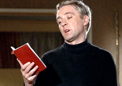 Screenshot aus dem Film Fahrenheit 451, 1966 West-Deutschland, Direktor: François Truffaut. Zu sehen ist Oskar Werner, der in einem roten Buch liest.